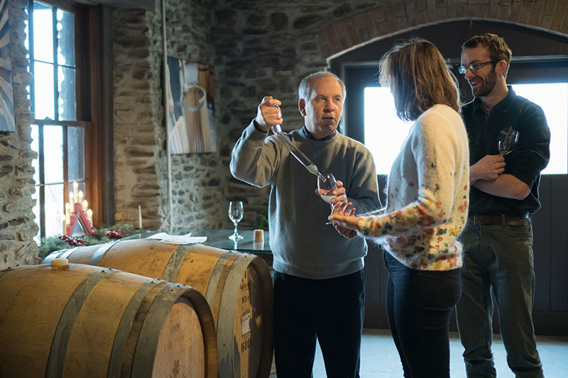 Allyn Brand using a wine thief to pour wine into a glass.