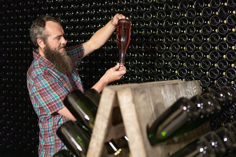 Eric Bauman holding a wine bottle upside down.