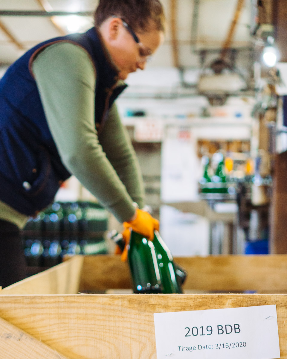 Katherine Hynes putting bottles in a wooden crate.