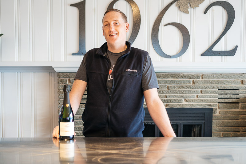 Steve Webster posing with a bottle of wine.