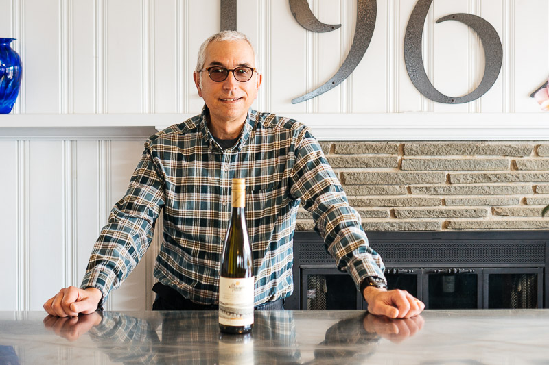 Paul Zorovich posing with a bottle of wine.