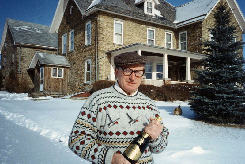 Willy Frank in front of Chateau holding a bottle of sparkling wine.