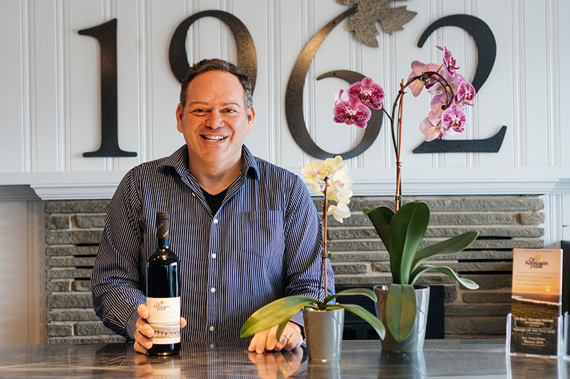 George Ditomasso posing for a picture with a bottle of wine.