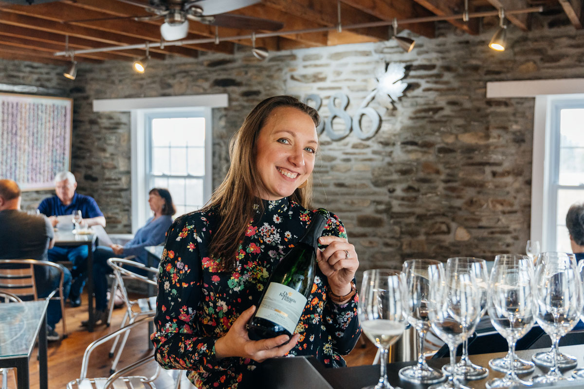 Holly Fusco smiling and holding a bottle of wine.