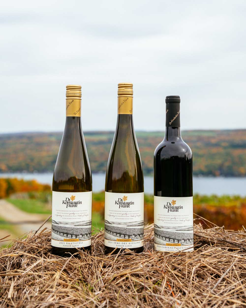 Three bottles of Rkatseteli, Semi-Dry Riesling, and Cabernet Sauvignon sitting on a pile of hay.