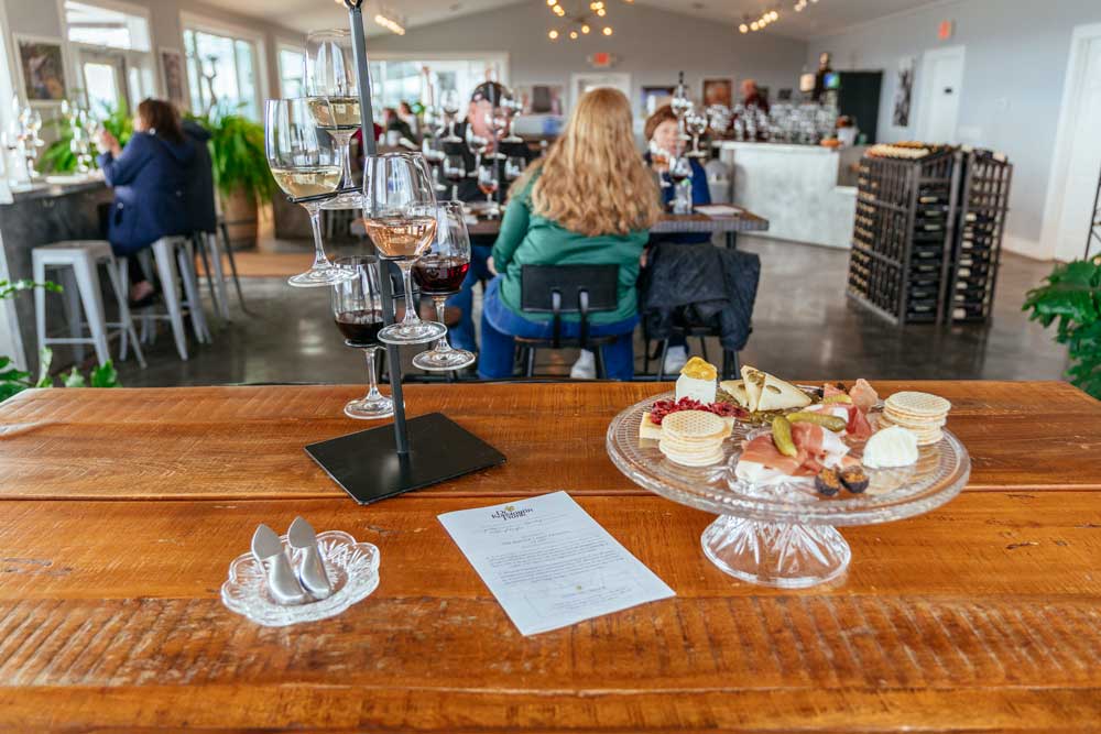 Flight of 5 wines in a tasting room with a cheese board.