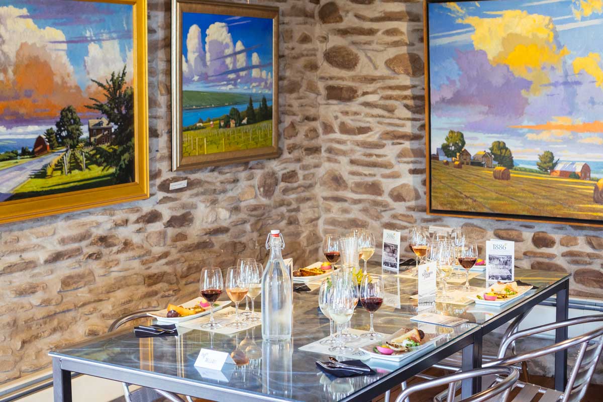 Table set with wine glasses and food with paintings hanging on the wall.