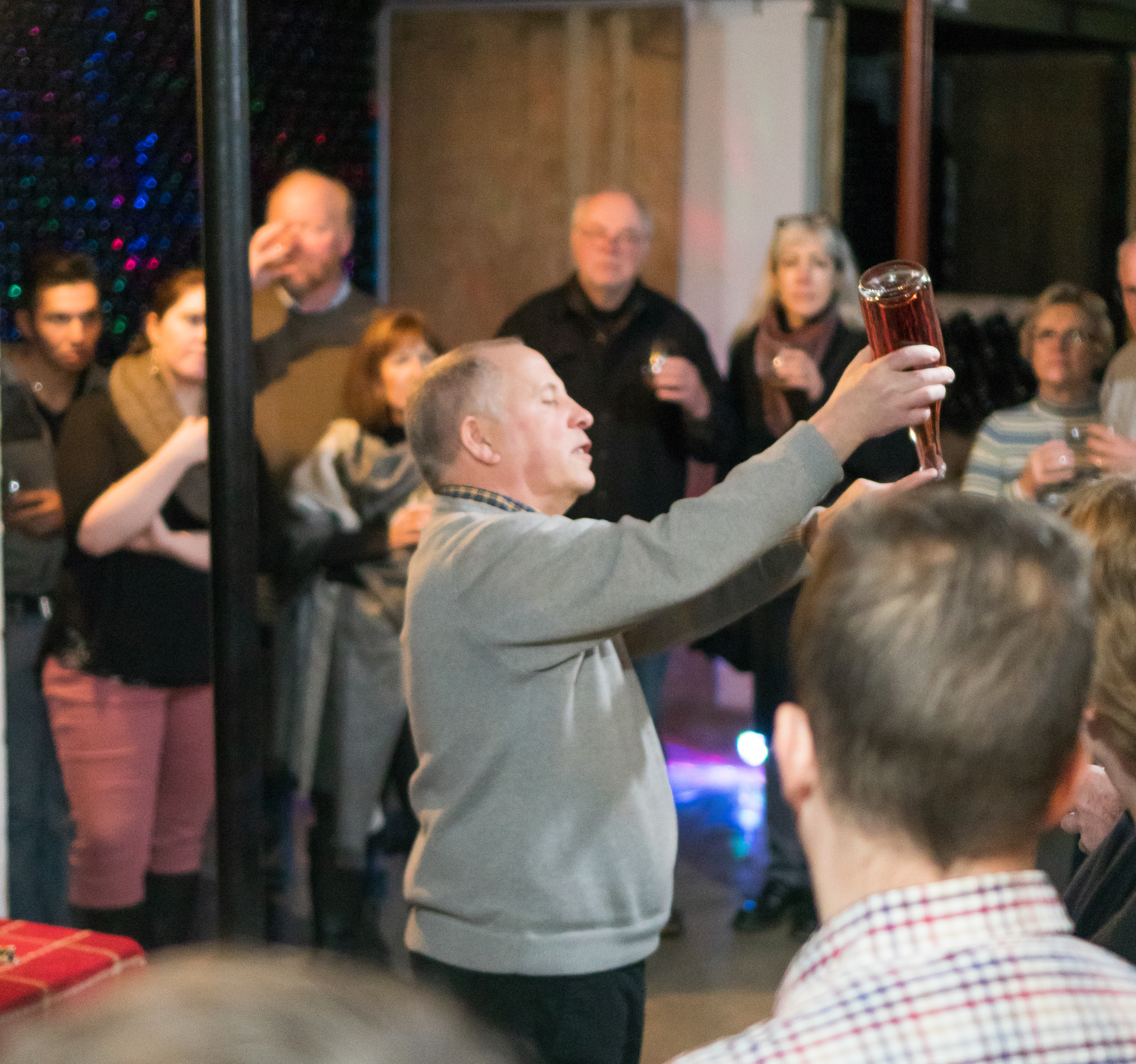 Allyn Brand holding a bottle of wine upside-down to show a group.